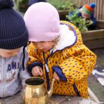 Children in garden looking into teapot