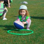 girl places rugby ball in inside green ring