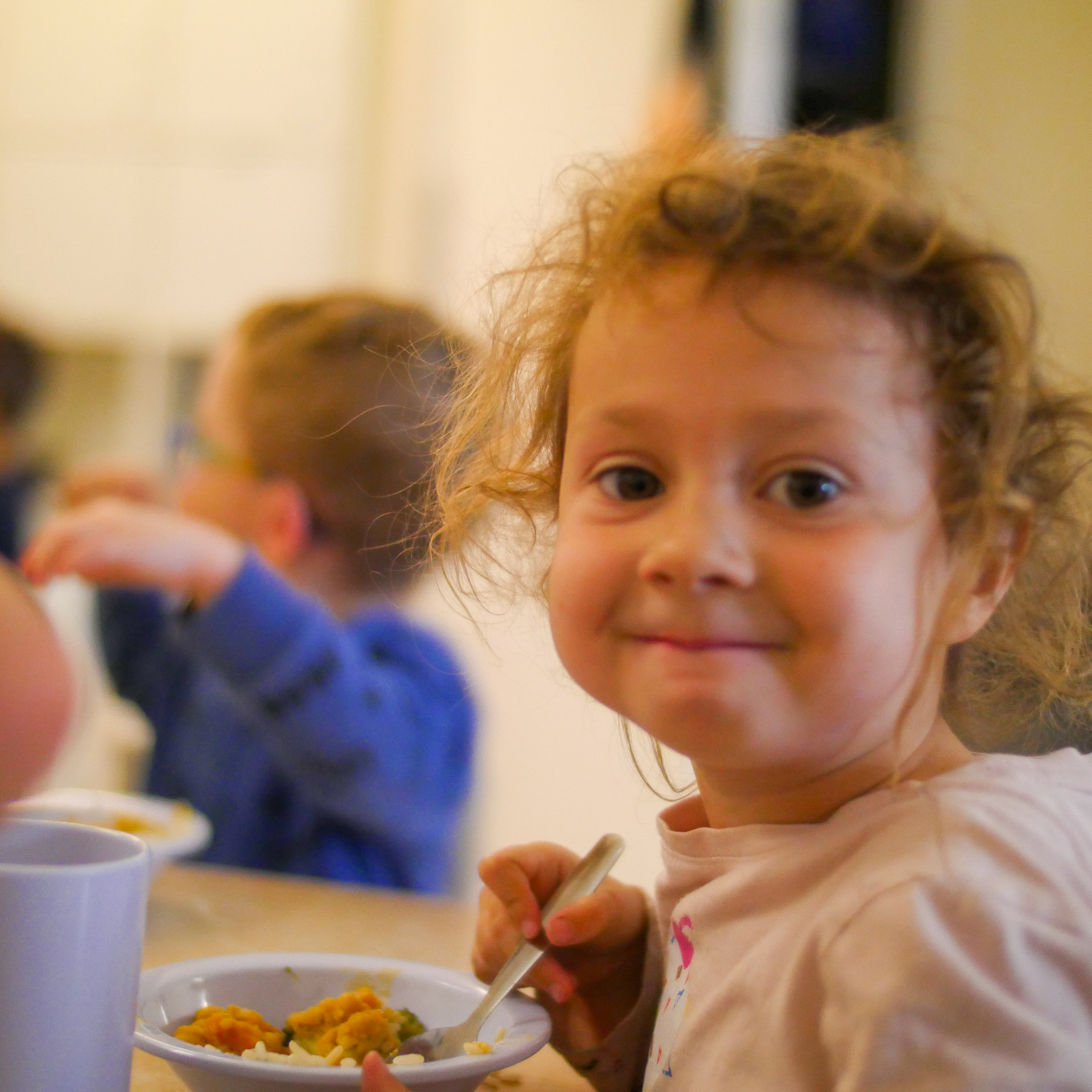 girl at the dinner table smiles at camera