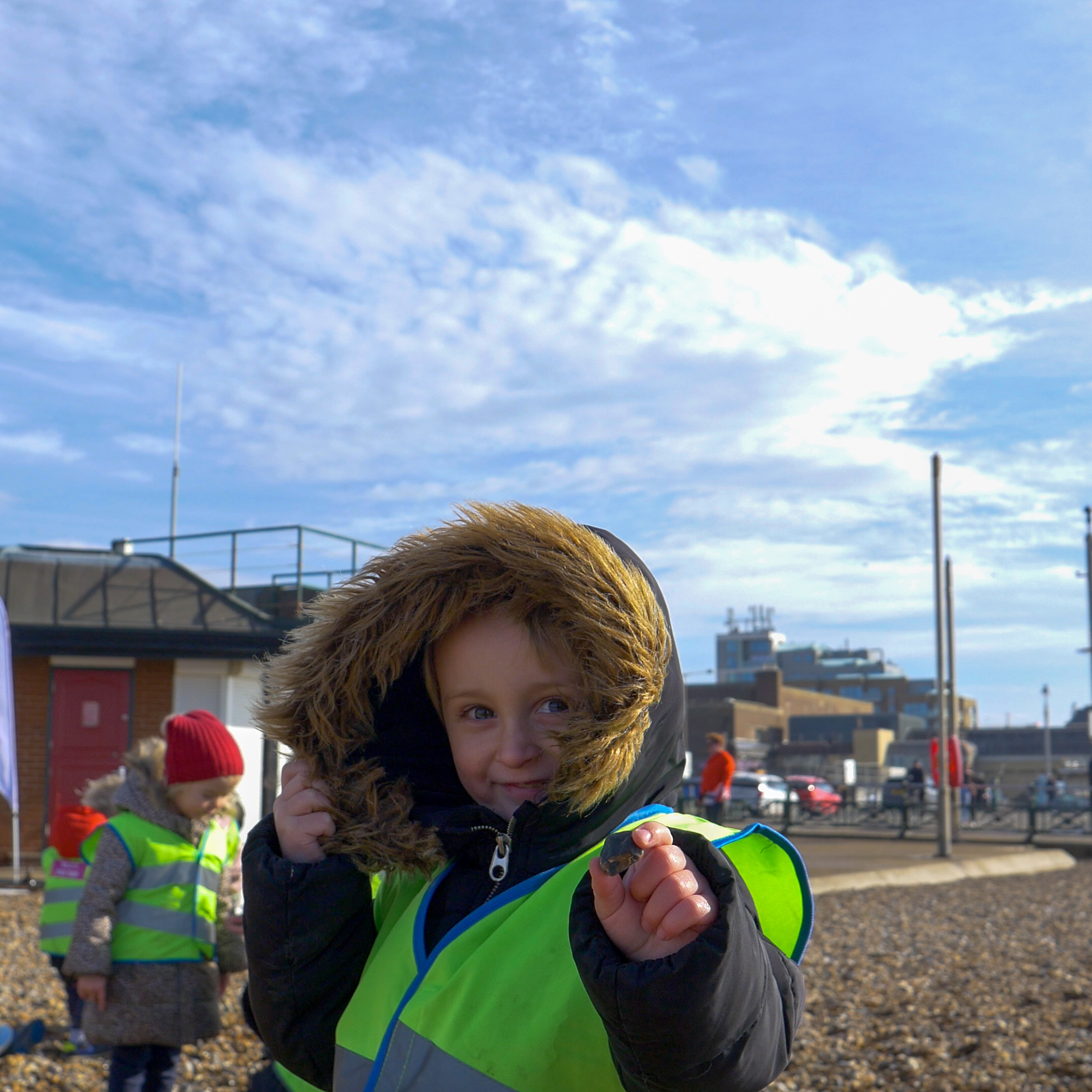 smiling boy showing stone to camera on a pebble beach