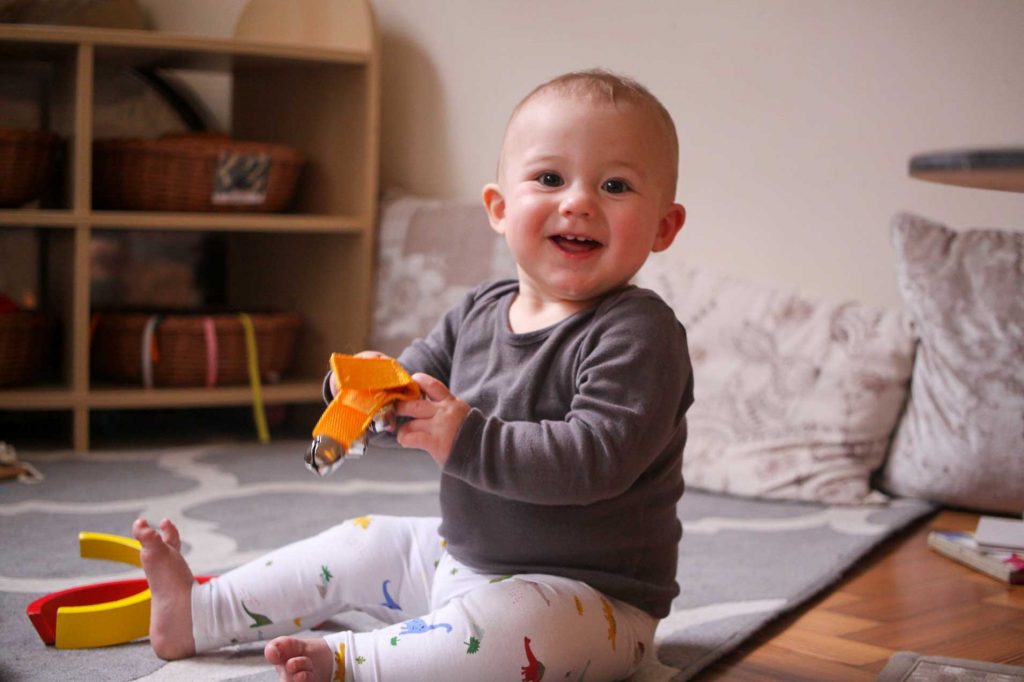 baby boy smiling while holding musical bells