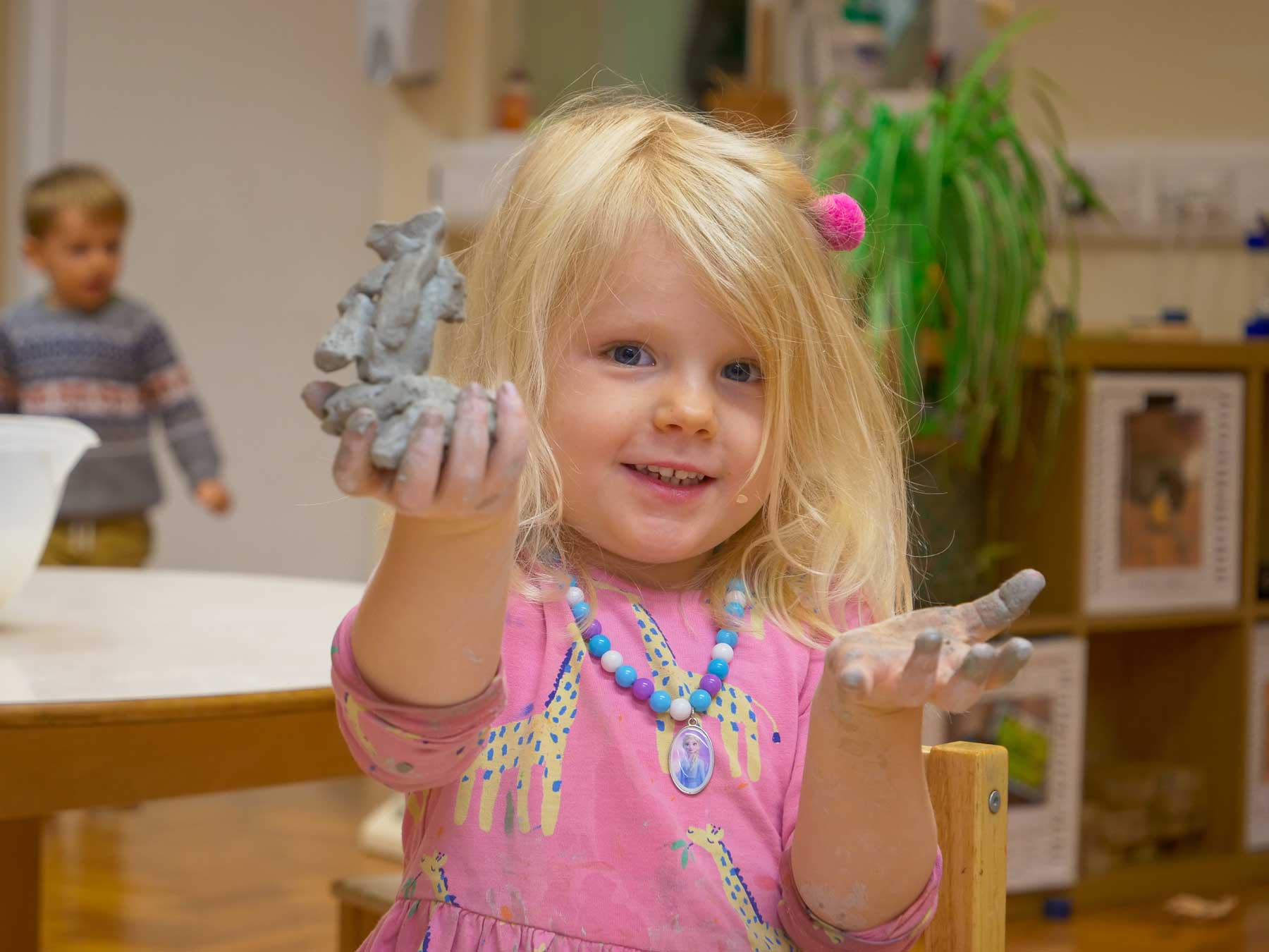 girl holding up home made clay model