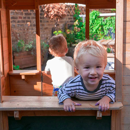 boy smiling through nursery garden playhouse