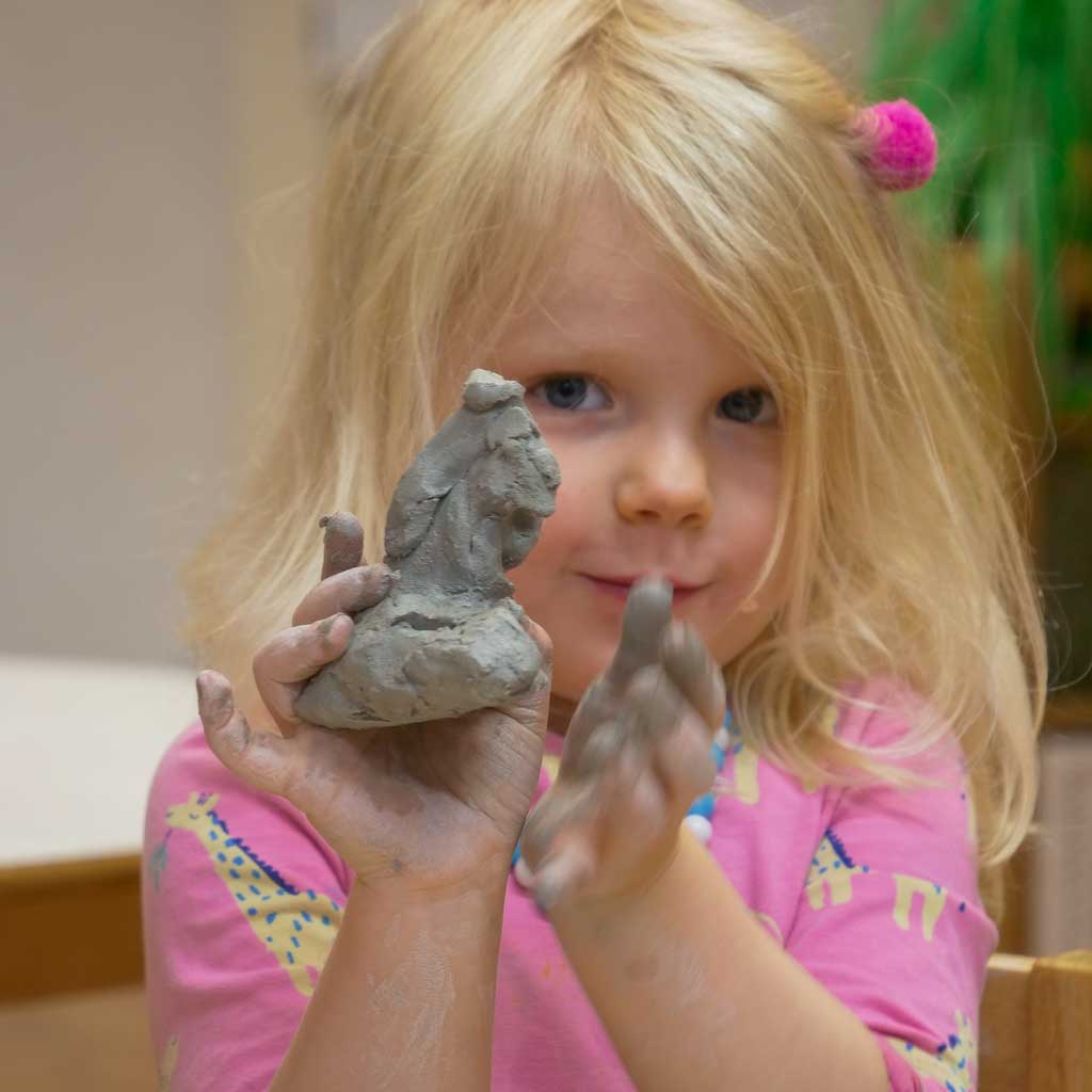 girl holding up home made clay model