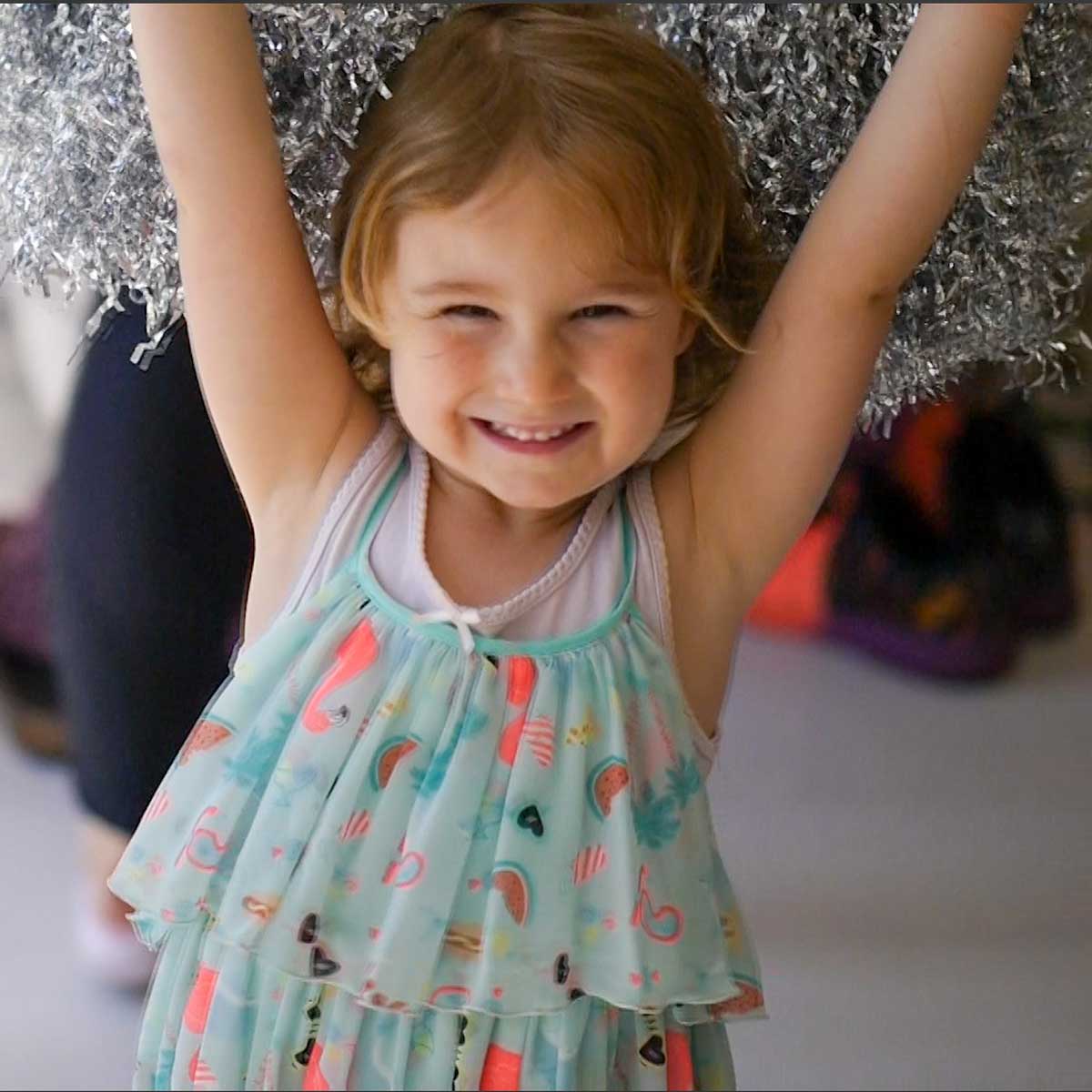 girl smiling with silver pom poms