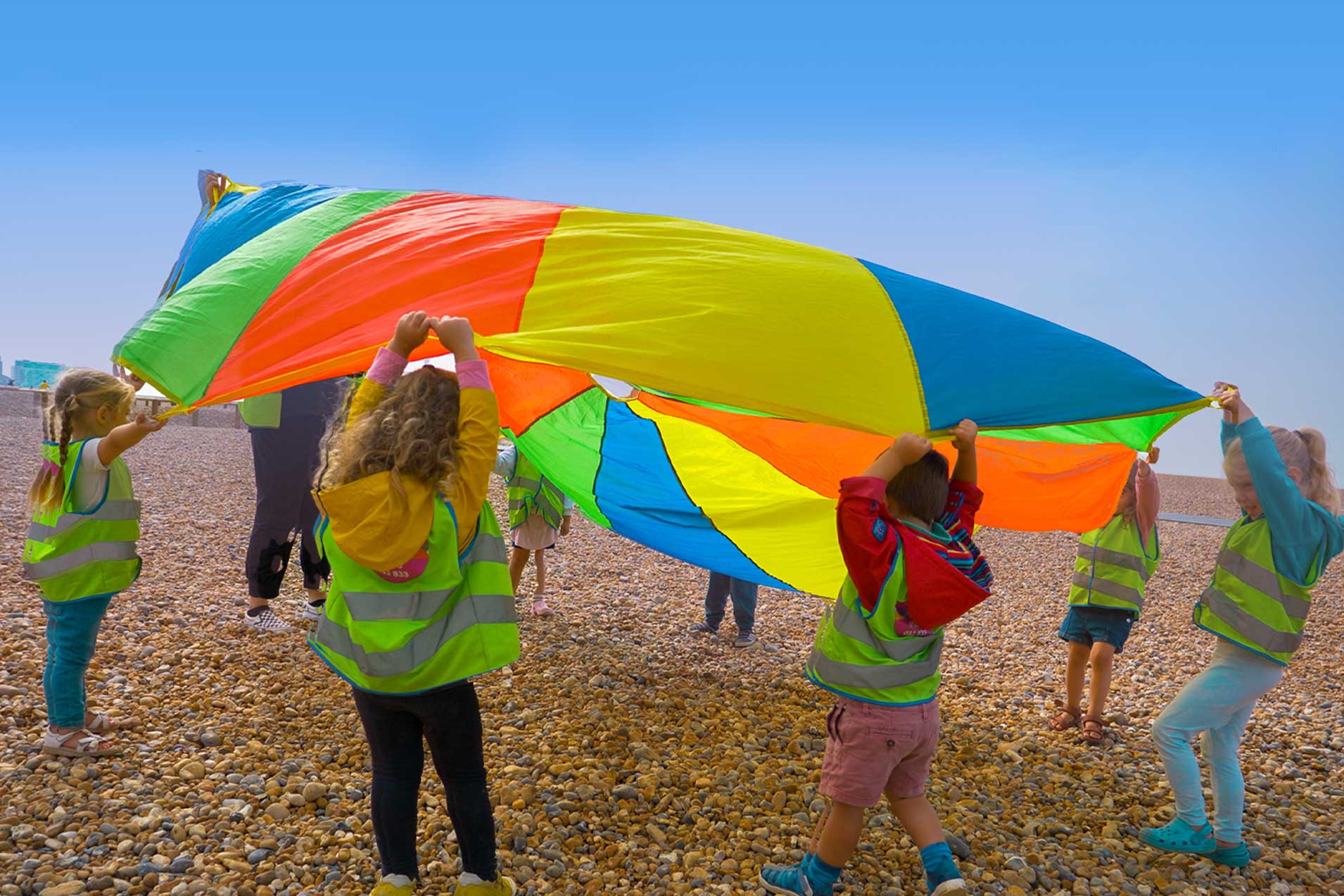 children on the beach with colourful parachute