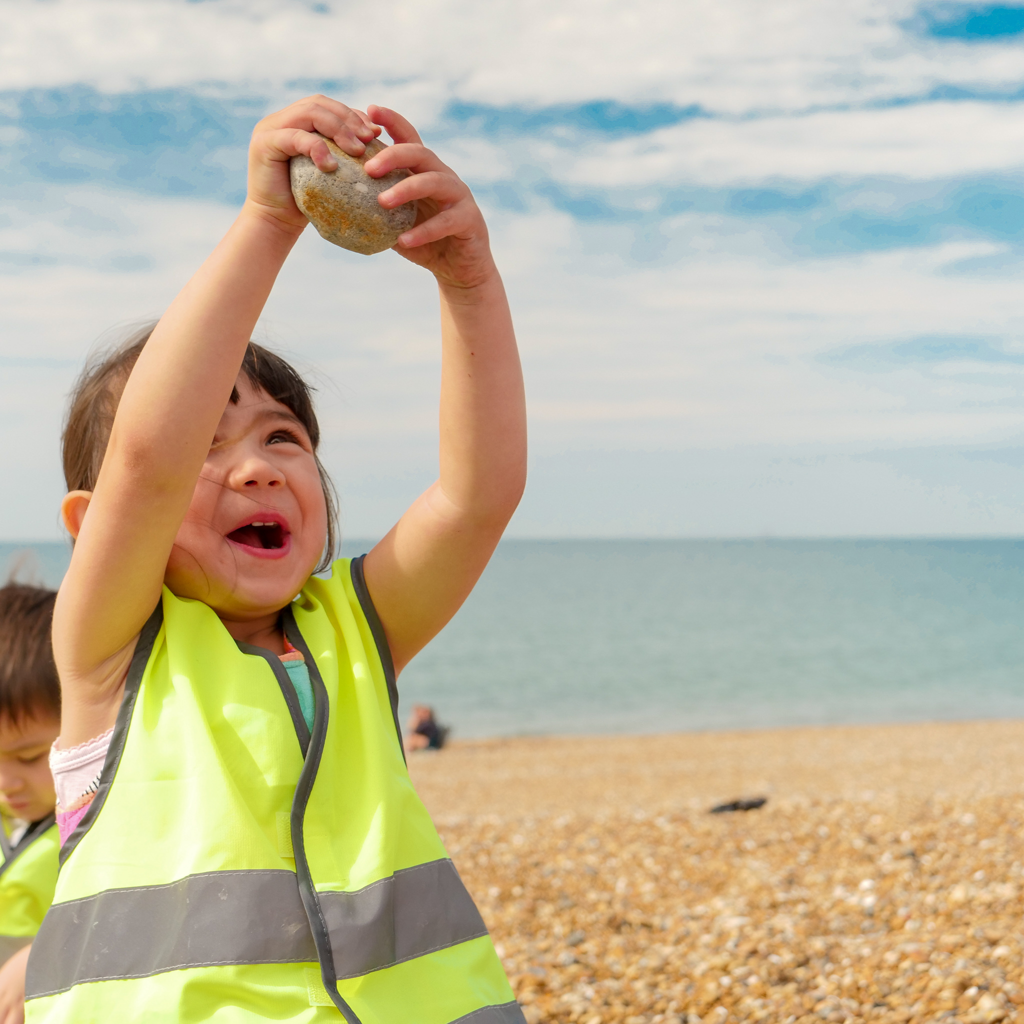 Girl holding up rock on the beach