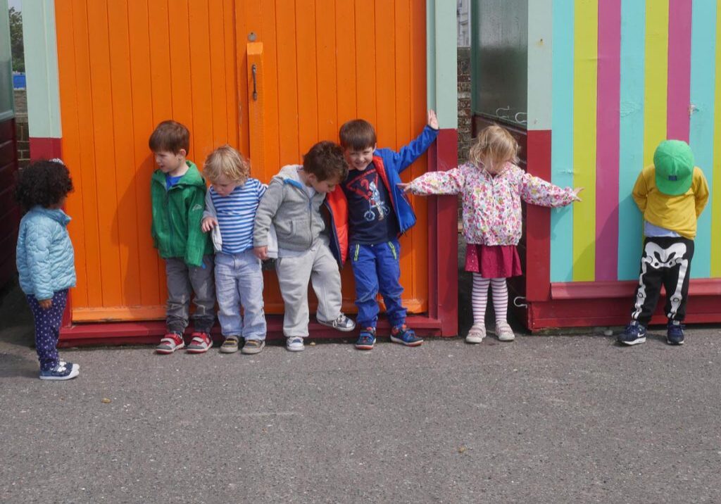 children stood outside colourful sheds